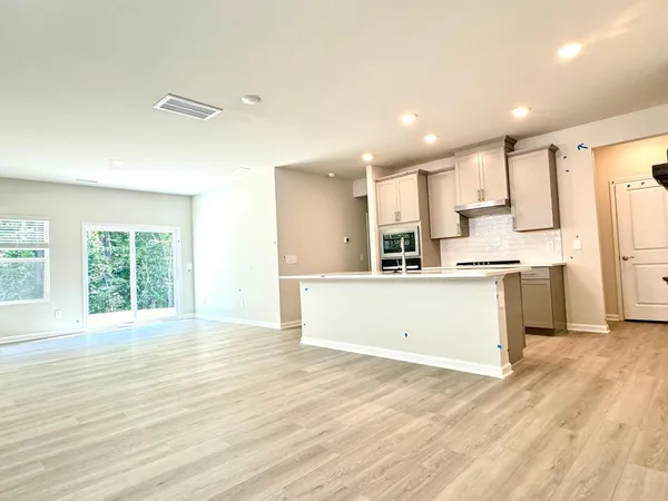 a view of kitchen with kitchen island a sink wooden floor and a refrigerator