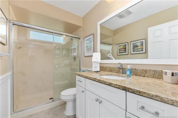 a bathroom with a granite countertop sink a toilet and shower