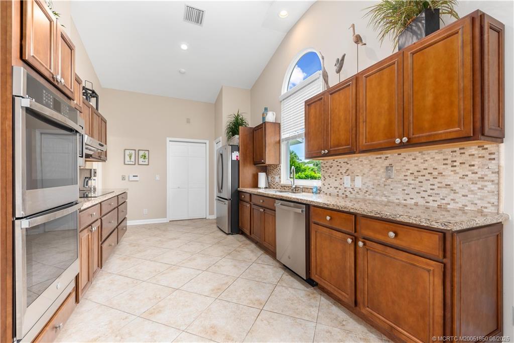 12813 Northwest Cinnamon Way Palm City, FL 34990 - Photo 9 of 33 a kitchen with stainless steel appliances granite countertop a refrigerator sink and cabinets
