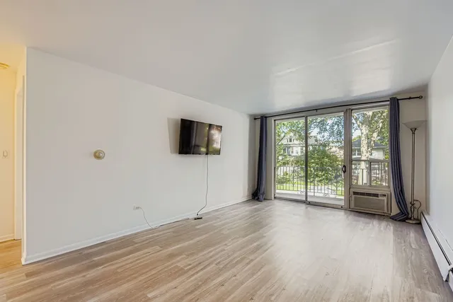 a view of an empty room with a window and wooden floor