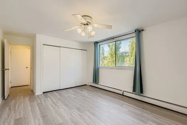 an empty room with wooden floor fan and windows