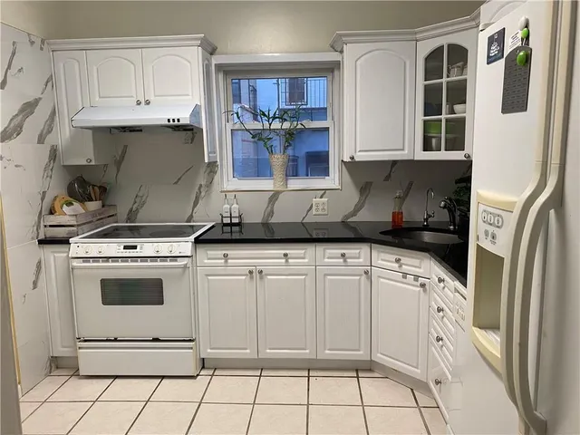 a kitchen with white cabinets and appliances