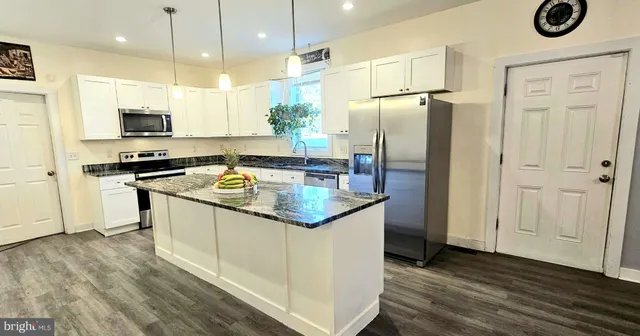 a kitchen with stainless steel appliances granite countertop a refrigerator a stove a sink and a microwave