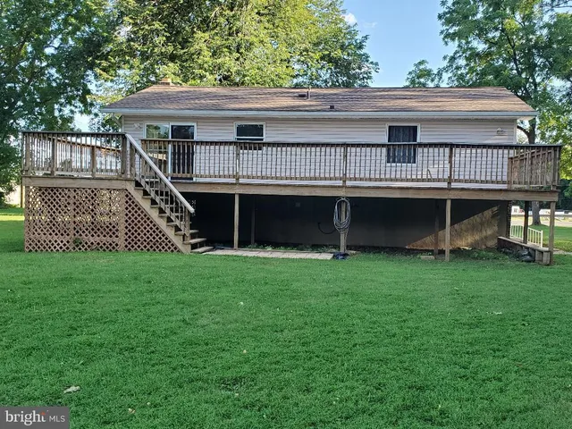 a view of house with a big yard and large trees