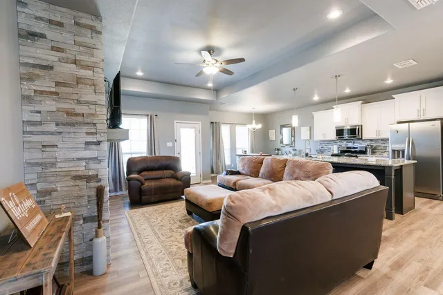 a living room with furniture kitchen view and a chandelier