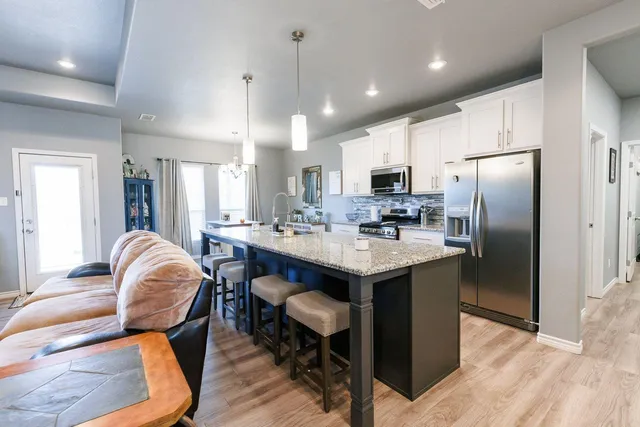 a kitchen with stainless steel appliances granite countertop a sink a stove a refrigerator cabinets and dining table