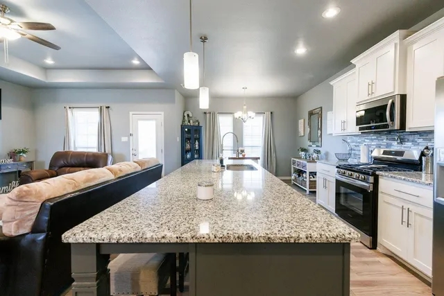 a kitchen with kitchen island granite countertop wooden floor and stainless steel appliances