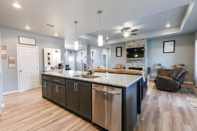 a kitchen with granite countertop a sink dishwasher a stove and a refrigerator with wooden floor