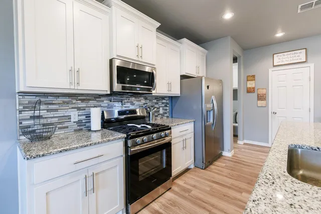 a kitchen with stainless steel appliances granite countertop a stove a refrigerator and a microwave