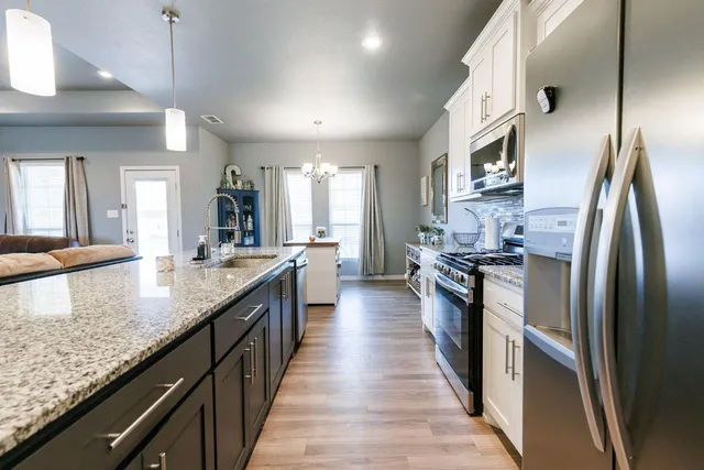 a large kitchen with granite countertop lots of counter top space and stainless steel appliances