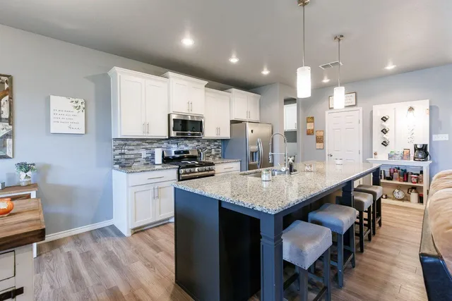 a kitchen with kitchen island granite countertop a sink a center island and stainless steel appliances