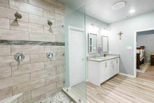a bathroom with a double vanity sink a mirror and shower