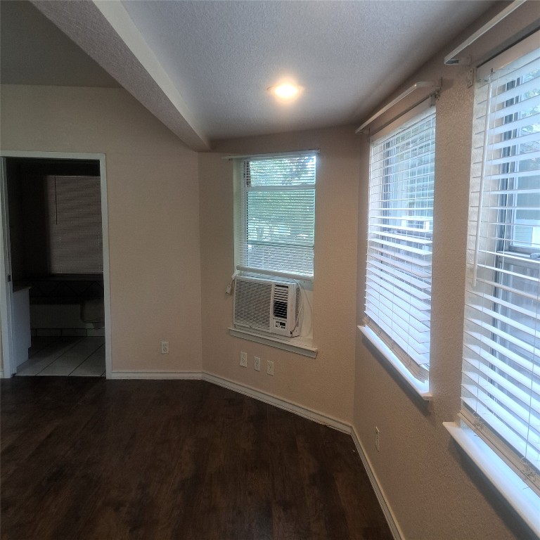 397 Lacy Drive, Unit B Elgin, TX 78621 - Photo 8 of 19 Unfurnished room featuring a textured ceiling, dark wood-style flooring, and cooling unit