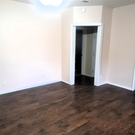 a view of an empty room with wooden floor and closet