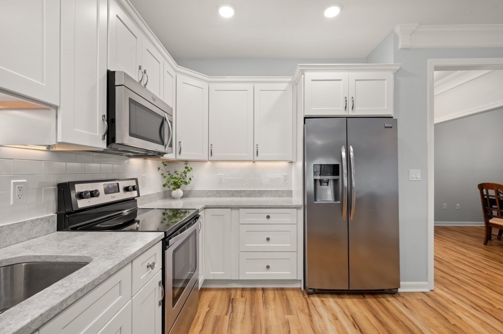 57 Augustus Court, Unit 1010 Reading, MA 01867 - Photo 12 of 32 a kitchen with stainless steel appliances and wooden cabinets