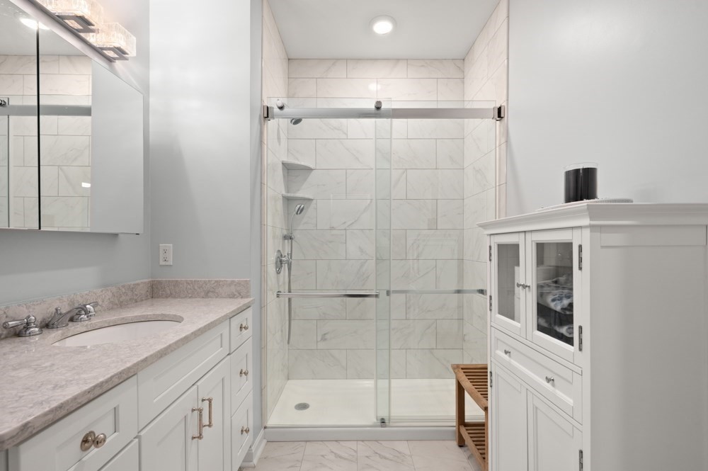 57 Augustus Court, Unit 1010 Reading, MA 01867 - Photo 24 of 32 a bathroom with a shower sink and mirror