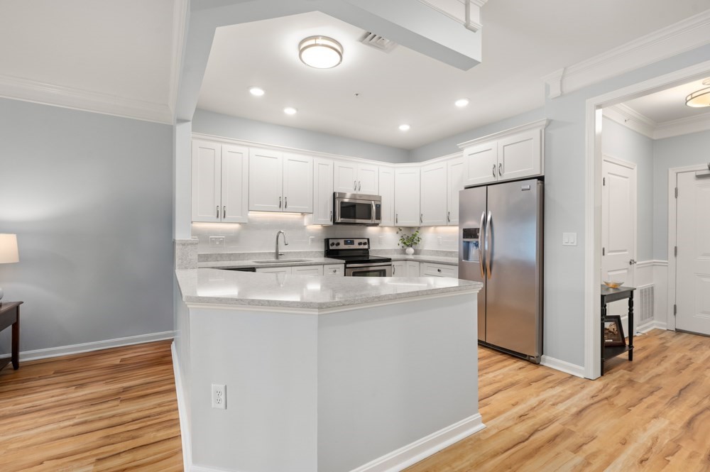 57 Augustus Court, Unit 1010 Reading, MA 01867 - Photo 8 of 32 a kitchen with stainless steel appliances granite countertop a refrigerator a stove a microwave and white cabinets with wooden floor