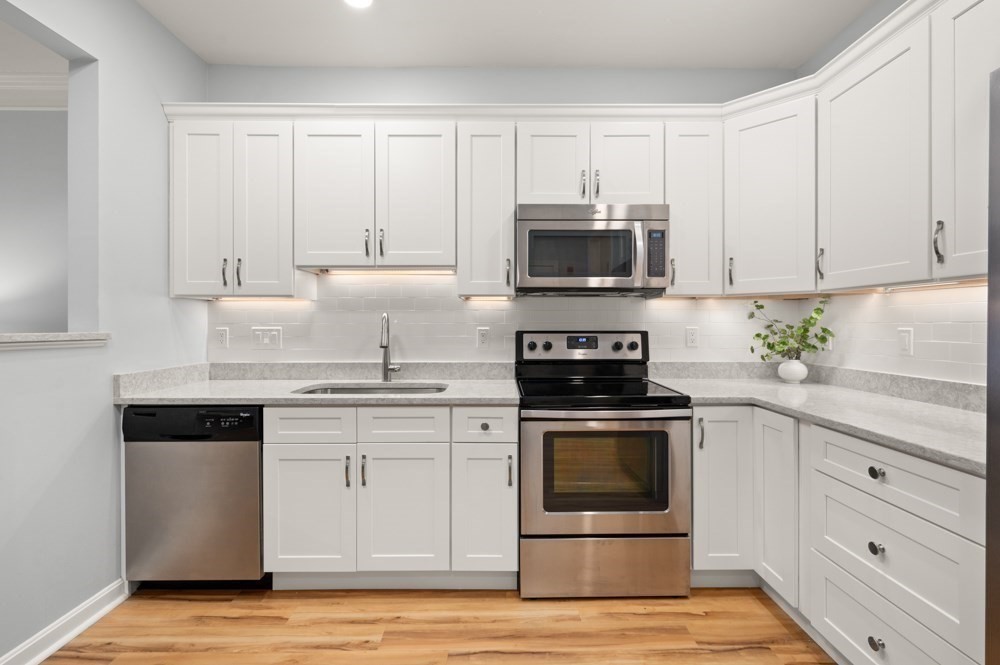 57 Augustus Court, Unit 1010 Reading, MA 01867 - Photo 9 of 32 a kitchen with white cabinets and stainless steel appliances