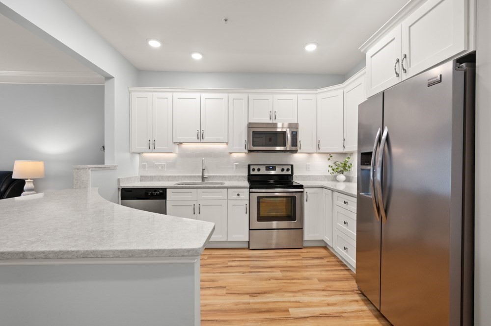 57 Augustus Court, Unit 1010 Reading, MA 01867 - Photo 10 of 32 a kitchen with kitchen island granite countertop white cabinets and stainless steel appliances