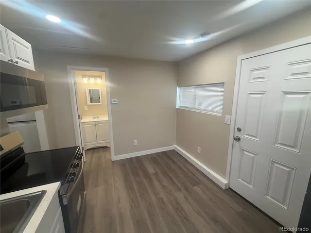 a kitchen with wooden floor and electronic appliances