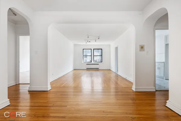 a view of empty room with wooden floor and fan