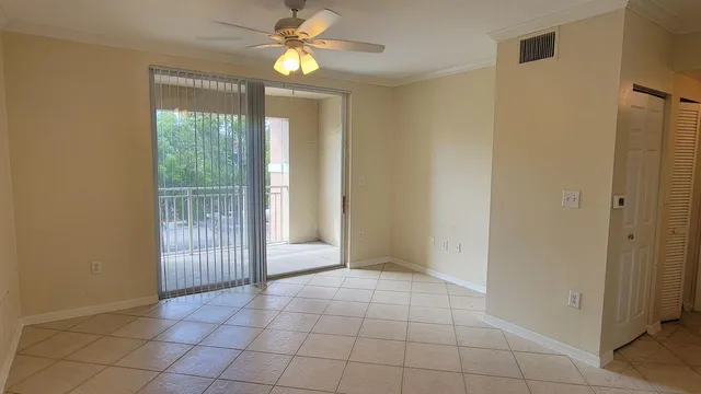 a view of an empty room with window and chandelier fan