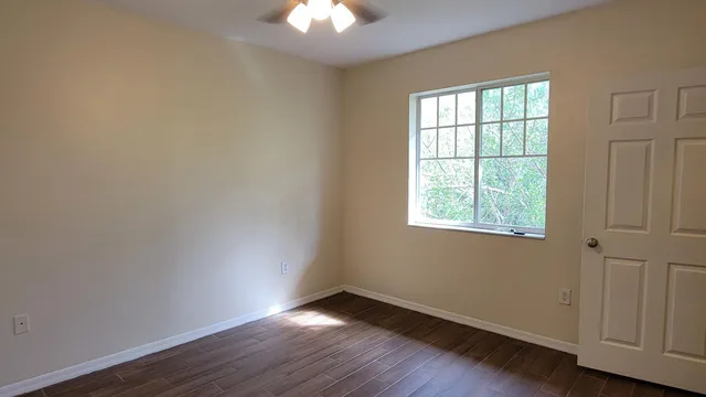 an empty room with wooden floor and windows