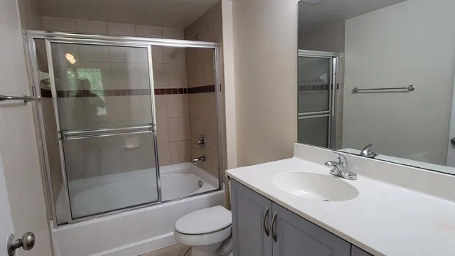 a bathroom with a shower sink vanity mirror and toilet
