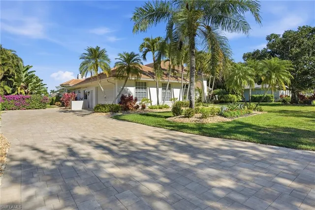 a front view of a house with a yard and palm trees