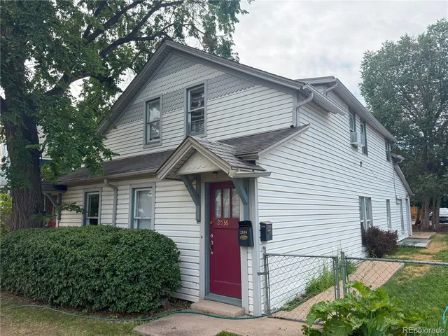 a view of a white house with a small yard and plants