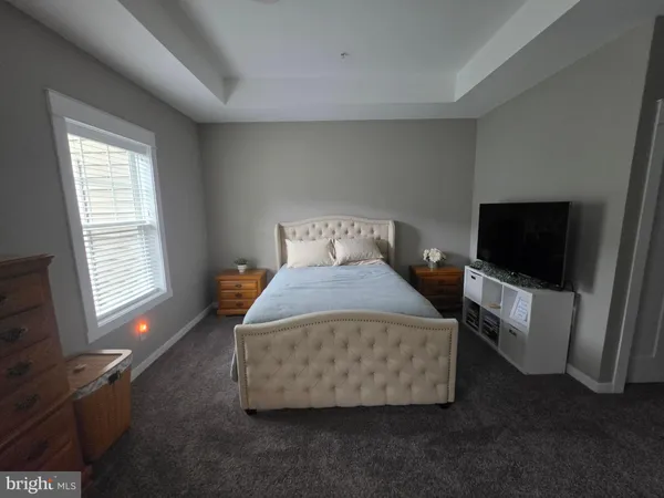 a bedroom with a bed and flat tv screen on the dresser