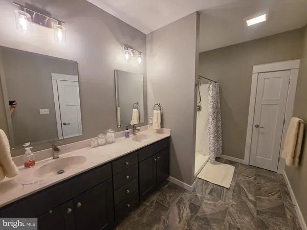 a spacious bathroom with a double vanity sink a large mirror and a shower