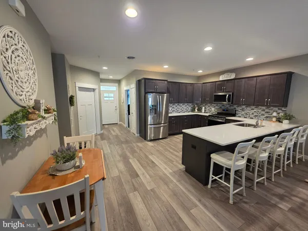 a kitchen with stainless steel appliances kitchen island granite countertop a table chairs and a refrigerator
