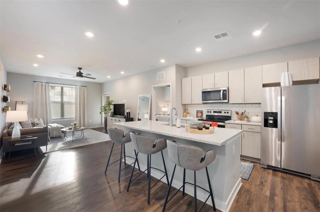 2201 Northwest Federal Highway, Unit 2B1314 Stuart, FL 34994 - Photo 2 of 47 a kitchen with stainless steel appliances a table chairs refrigerator and cabinets