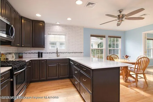 a kitchen with stainless steel appliances granite countertop a sink a stove a refrigerator cabinets and dining table