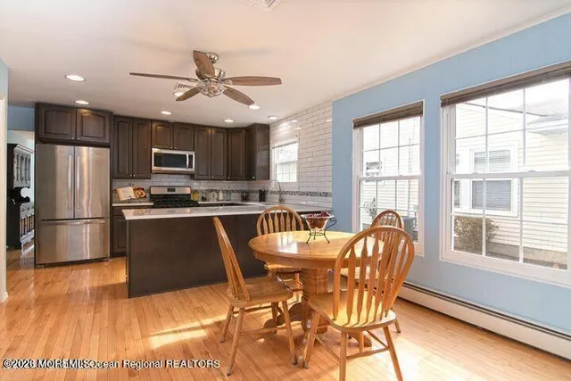 a kitchen with stainless steel appliances granite countertop a refrigerator a stove a sink a dining table and chairs with wooden floor