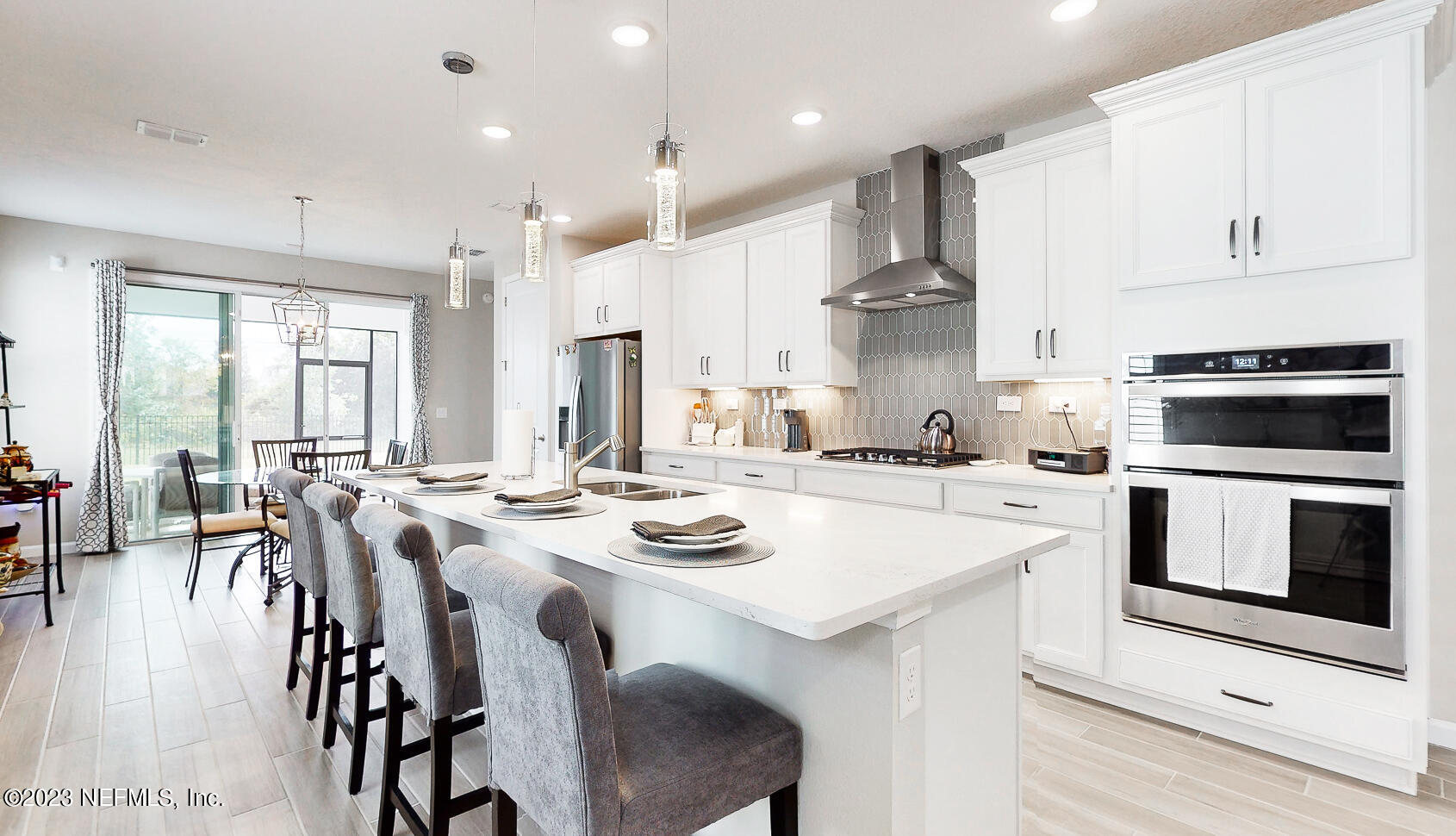 1113 Rustic Ml Drive St. Augustine, FL 32092 - Photo 8 of 62 a kitchen with a stove a kitchen island white cabinetry and couches with wooden floor