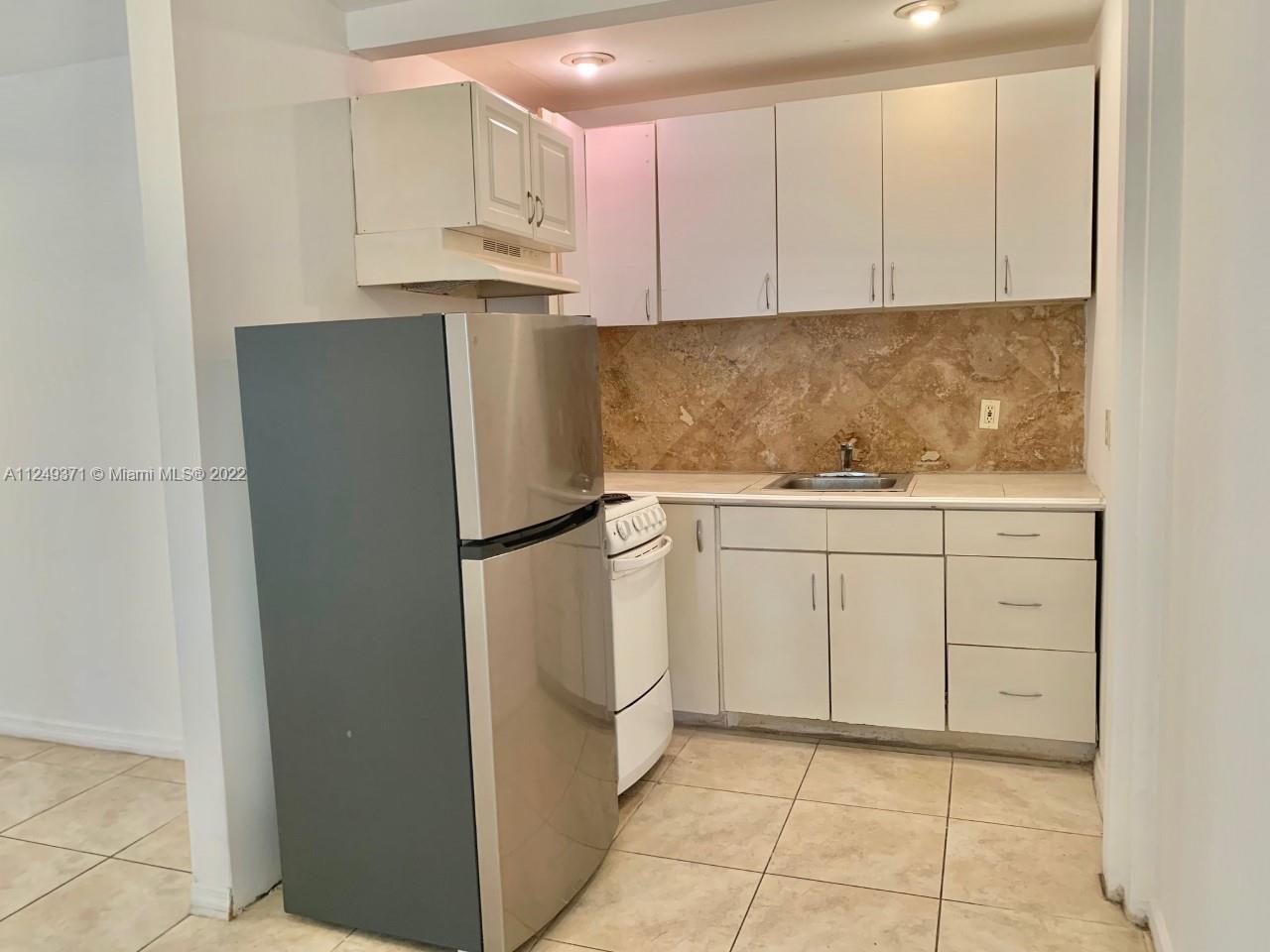a kitchen with white cabinets and refrigerator