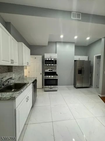 a kitchen with stainless steel appliances granite countertop a refrigerator and a stove