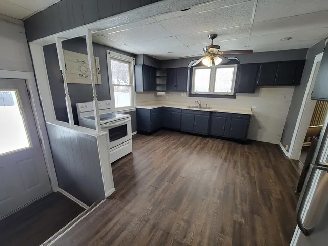 a kitchen with stainless steel appliances a refrigerator a sink dishwasher a stove and white countertops with wooden floor