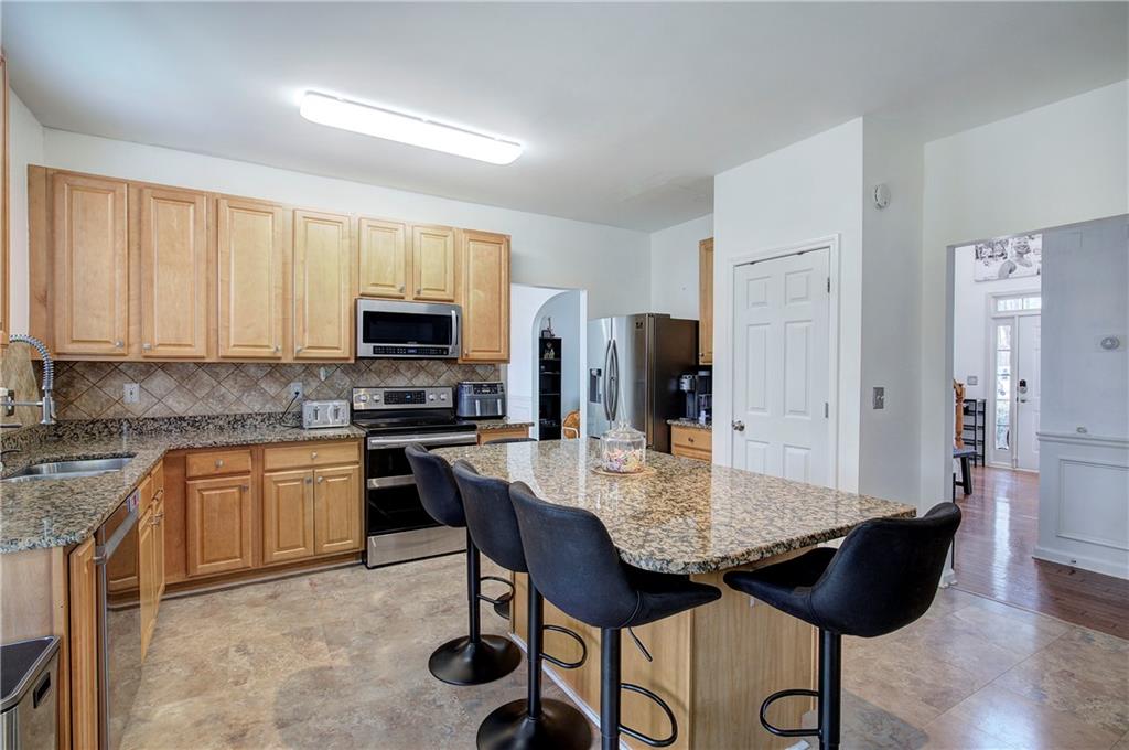 4508 Howell Farms Road Northwest Acworth, GA 30101 - Photo 13 of 42 a kitchen with stainless steel appliances granite countertop a stove a refrigerator a sink a dining table and chairs with wooden floor