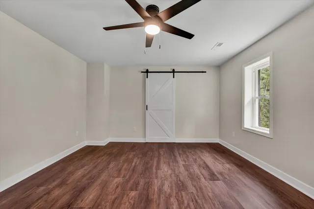 a view of empty room with wooden floor and fan