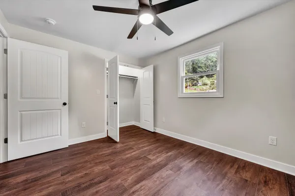 a view of an empty room with wooden floor and window