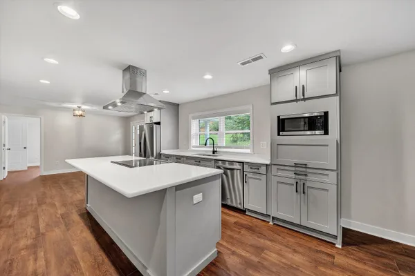 a kitchen with kitchen island a sink appliances and cabinets