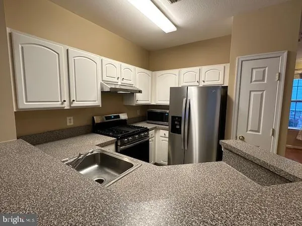 a kitchen with stainless steel appliances granite countertop a refrigerator stove and sink