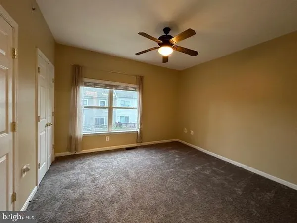 a view of an empty room with chandelier fan and fire place