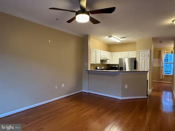 a view of kitchen with stainless steel appliances wooden floor and a refrigerator