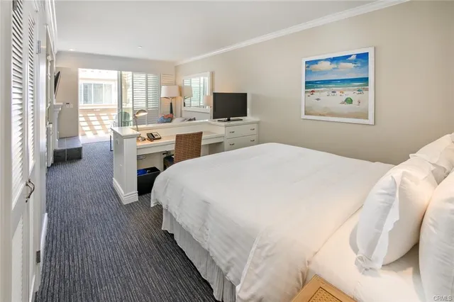 a spacious bedroom with a bed a computer on desk and a window