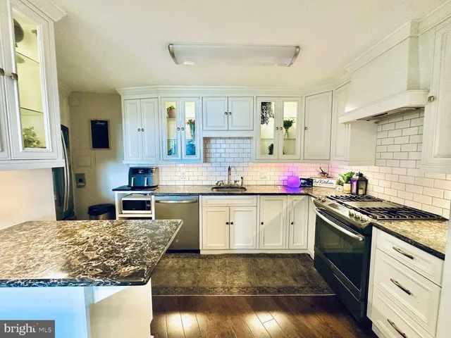 a kitchen with granite countertop a sink stove and cabinets