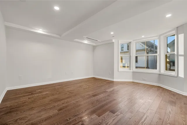 a view of an empty room with wooden floor and windows
